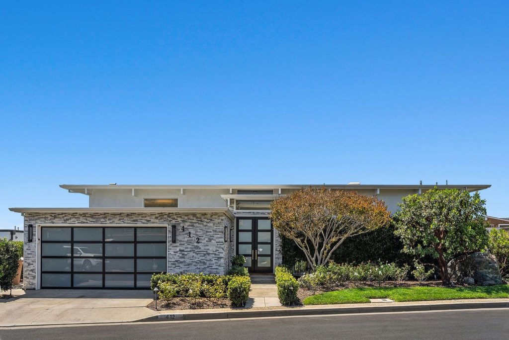 Low-slung mid-century modern home with stacked stone and glass garage door